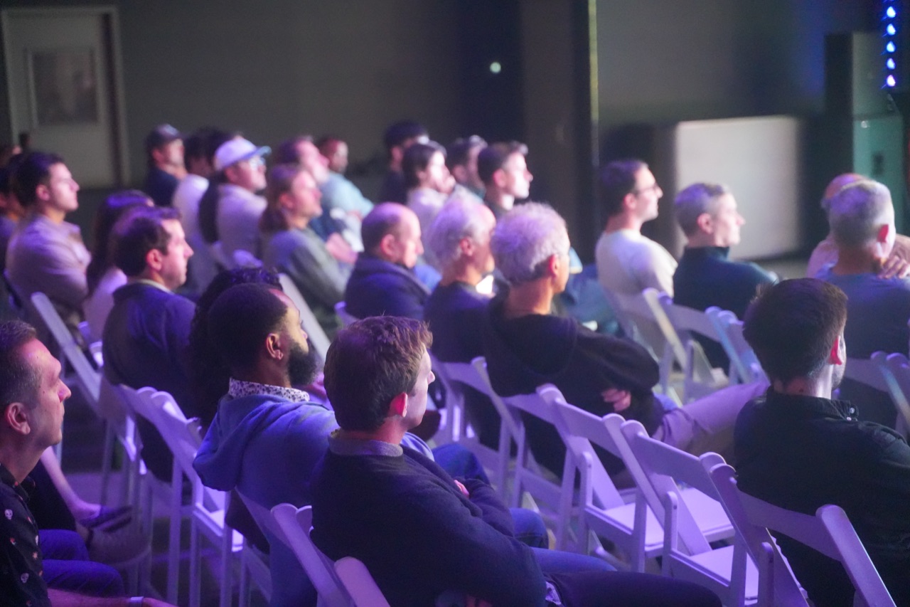 Audience filling every row at Startup Arena, listening to a pitch on the stage