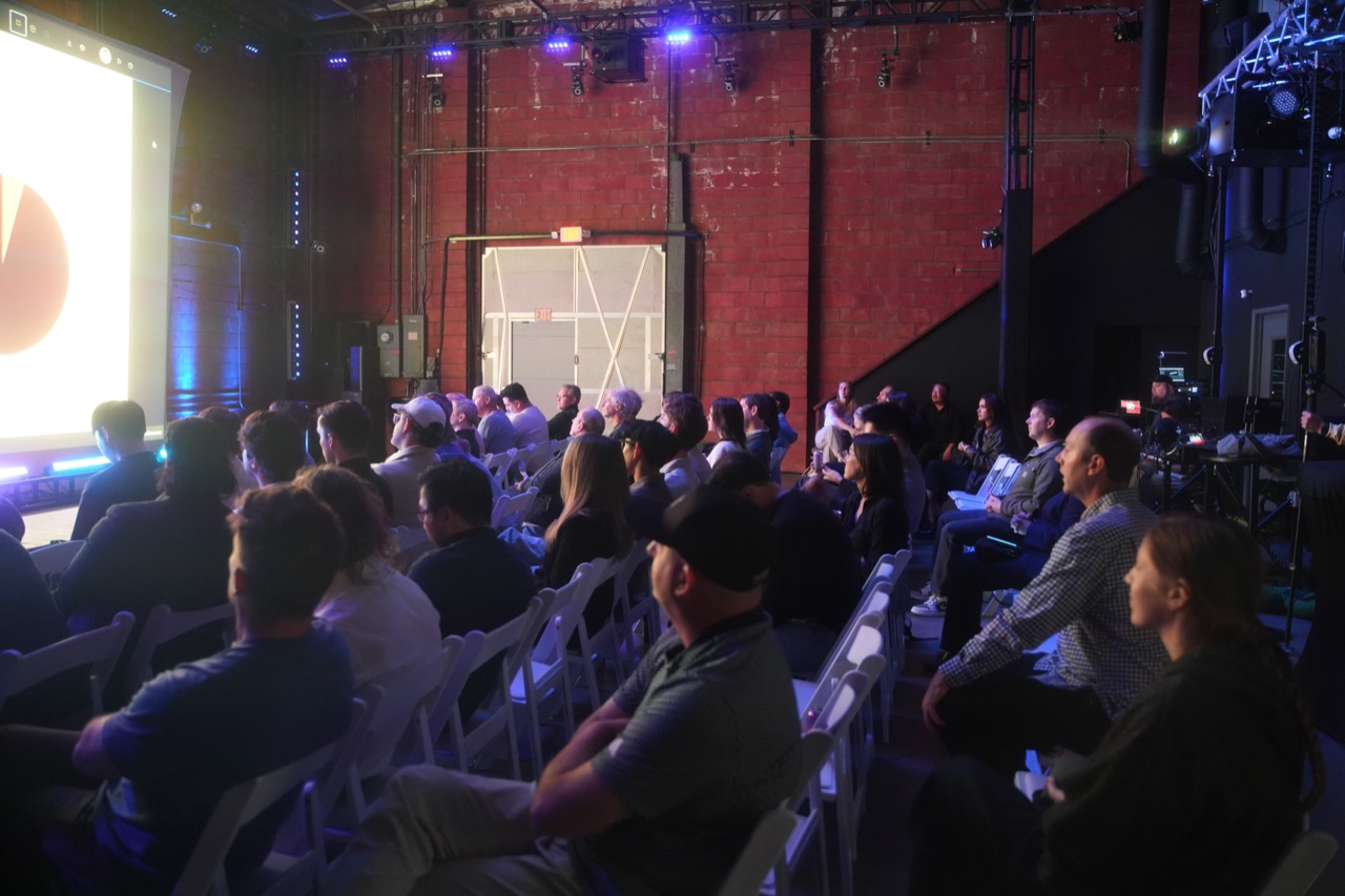 Side view of packed chairs at Startup Arena, red brick wall, logo lit on the stage