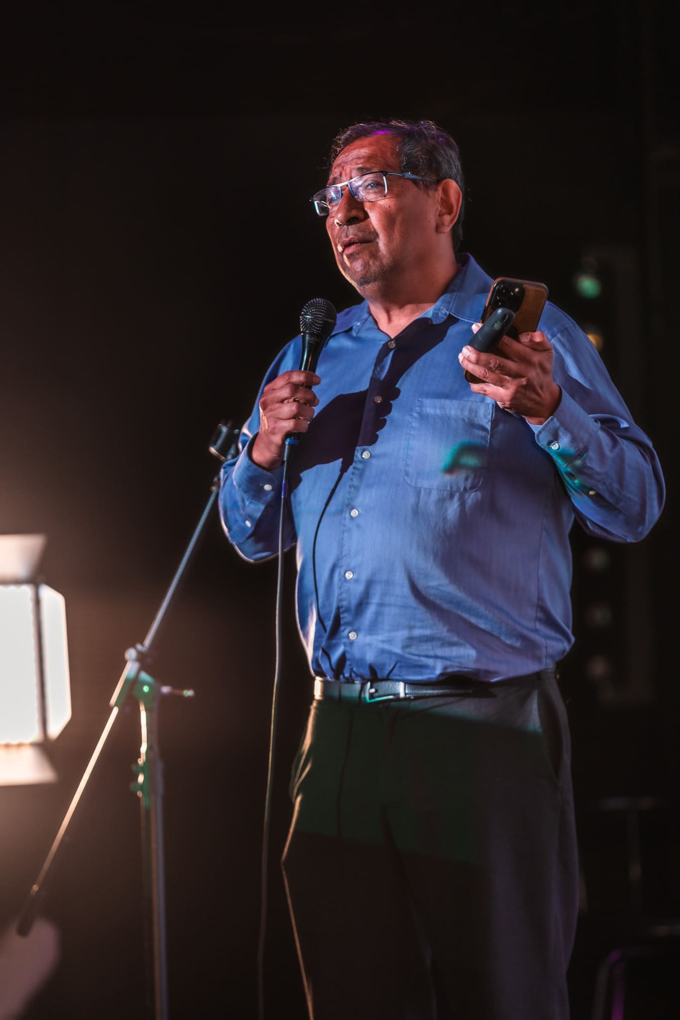 Wilson Hago of Hago Energetics presenting with mic and phone in hand, lit by a stage softbox