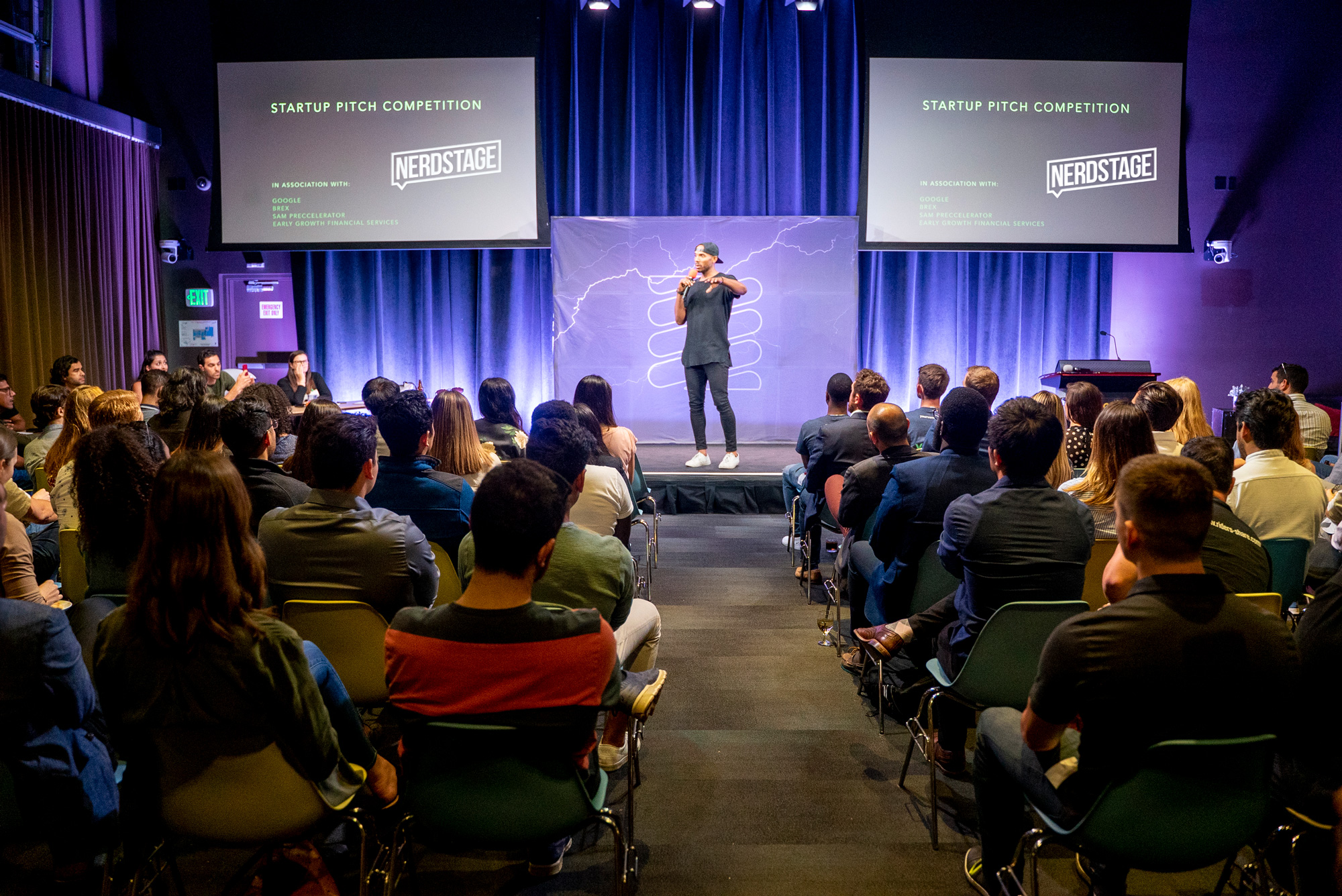 Founder pitching on stage at Startup Arena with a packed audience